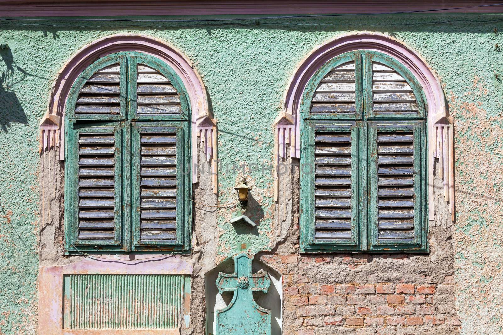 Brasov, Romania - June 9, 2013: Green old house windows with wood curtains from Brasov, Romania