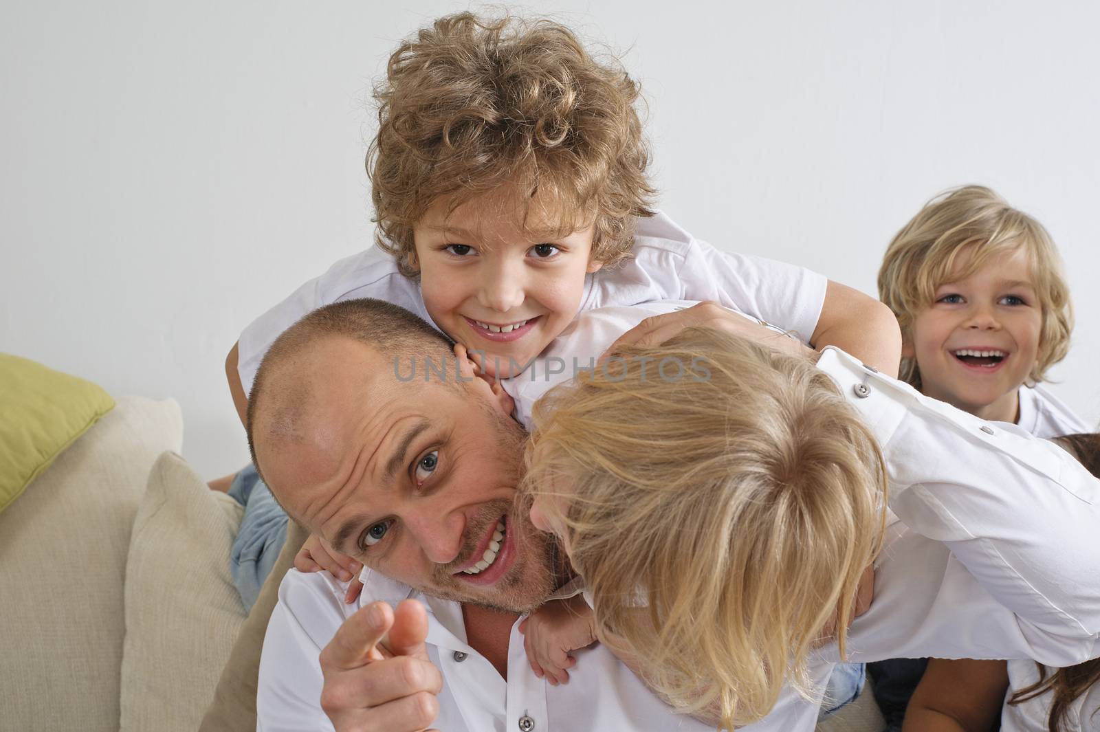Children climbing over their father on the sofa