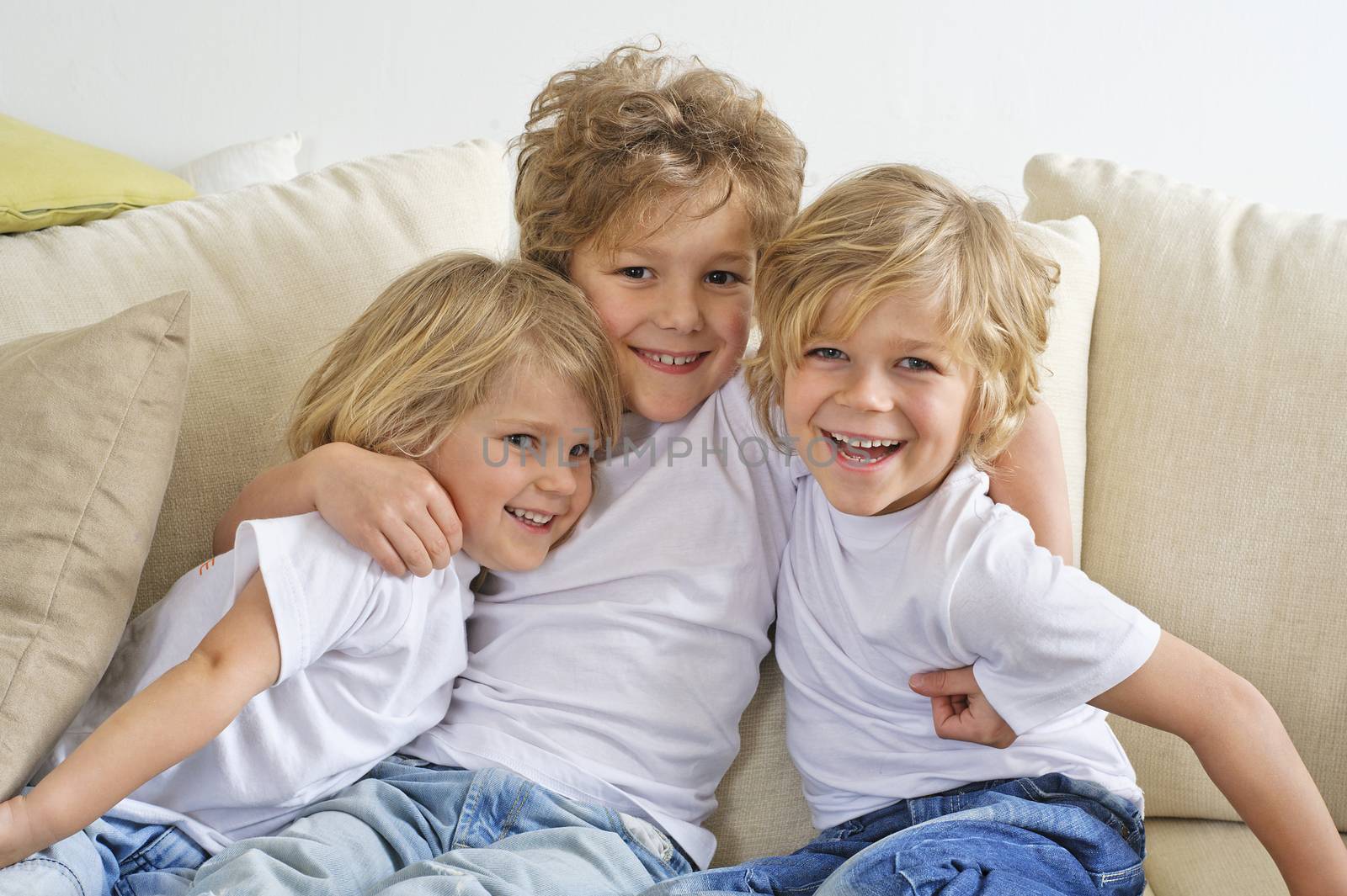 Three brothers hugging and playing on the sofa