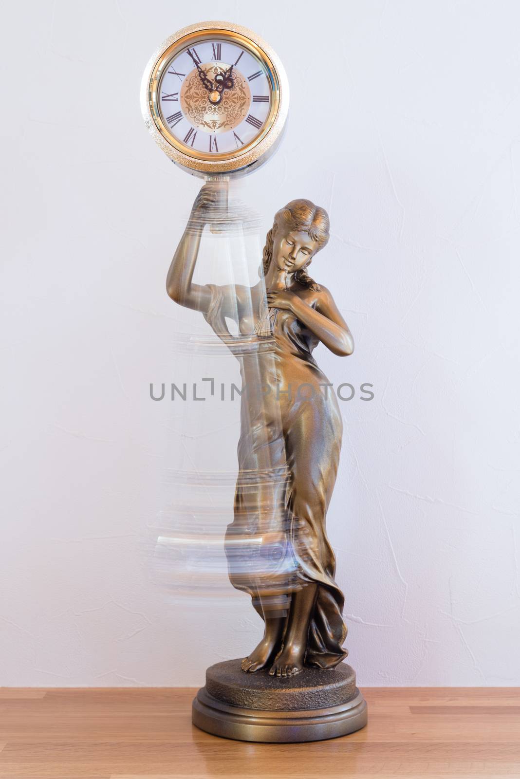 A classic looking bronze statue clock with a swinging pendulum.