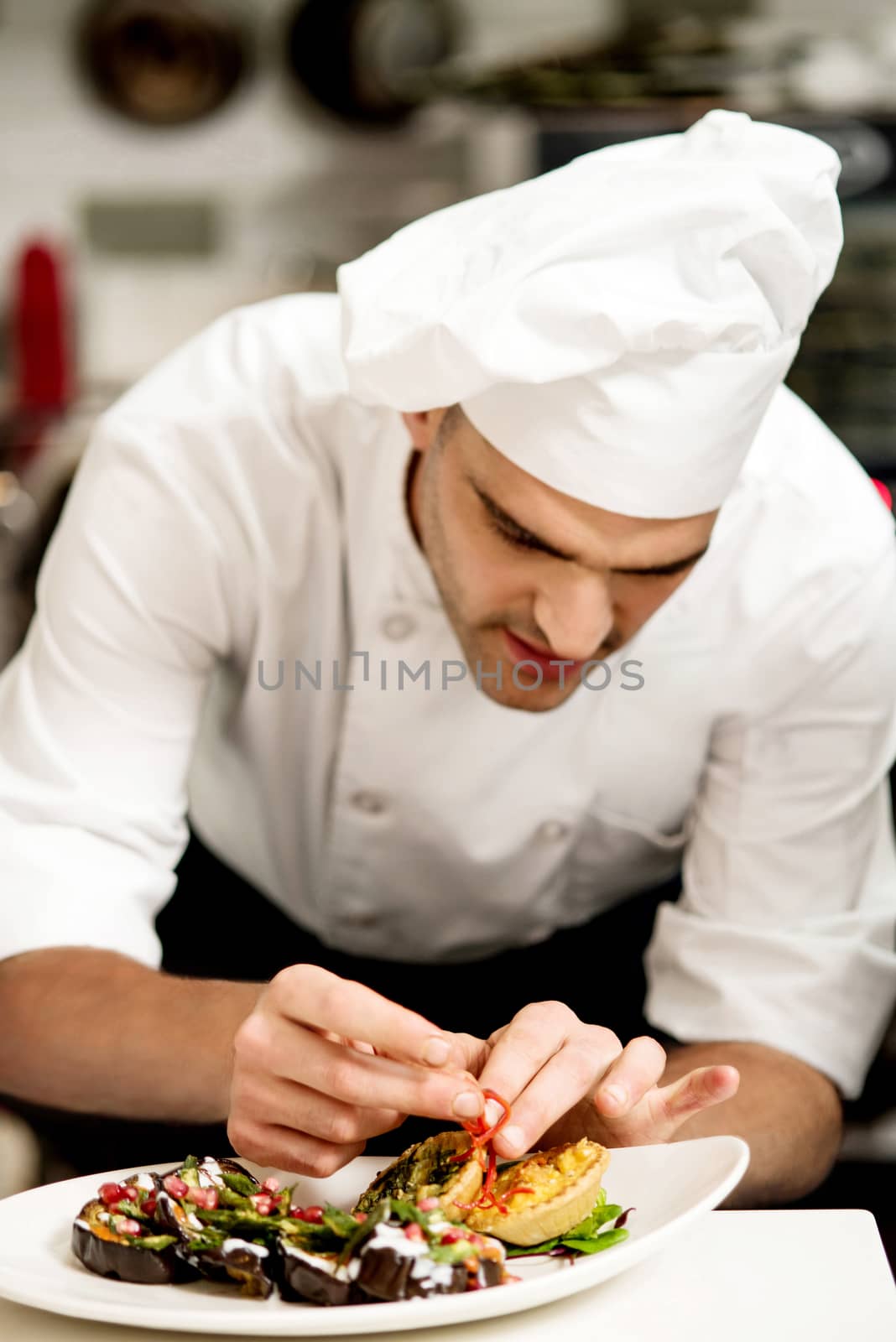 Male chef decorating salad of aubergine