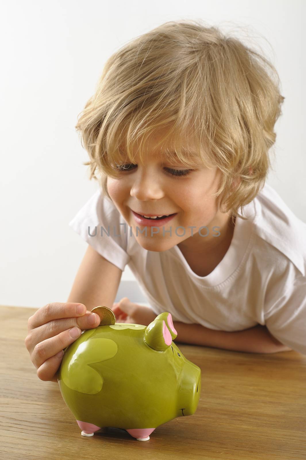 young boy puts a coin into his piggy bank
