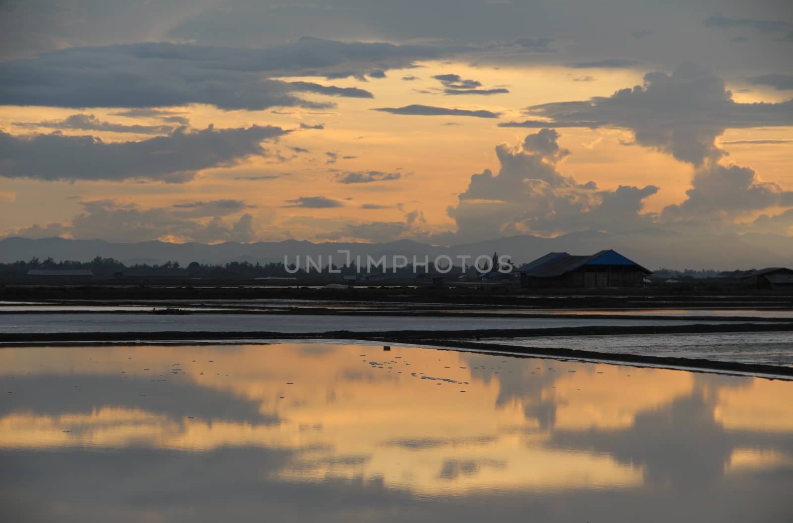 The reflection of clouded sky on salt pan field. by kpoppie