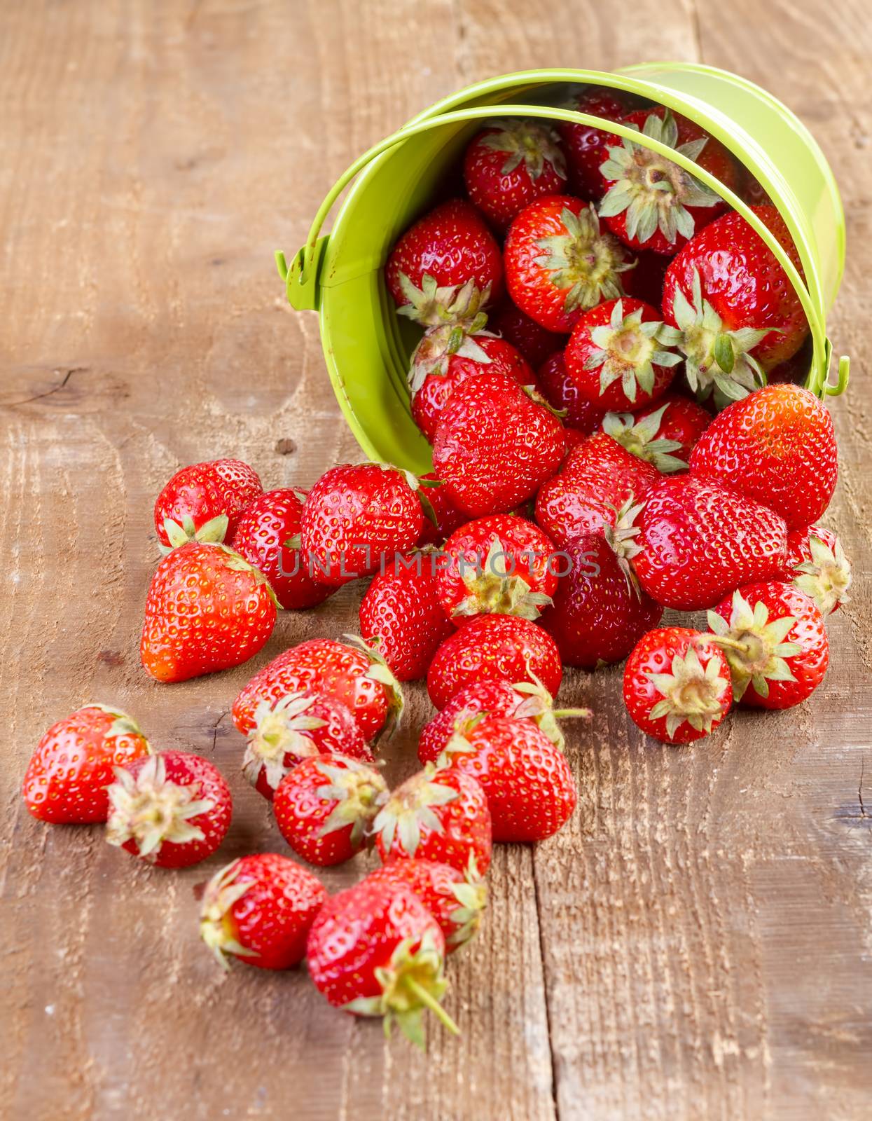 strawberry in a green metal bucket on wooden background