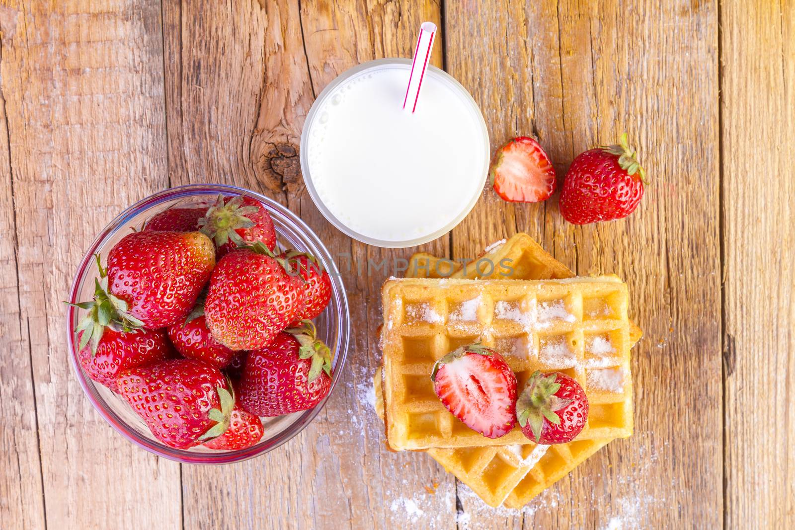 homemade waffles with strawberries and glass with milk on wooden background