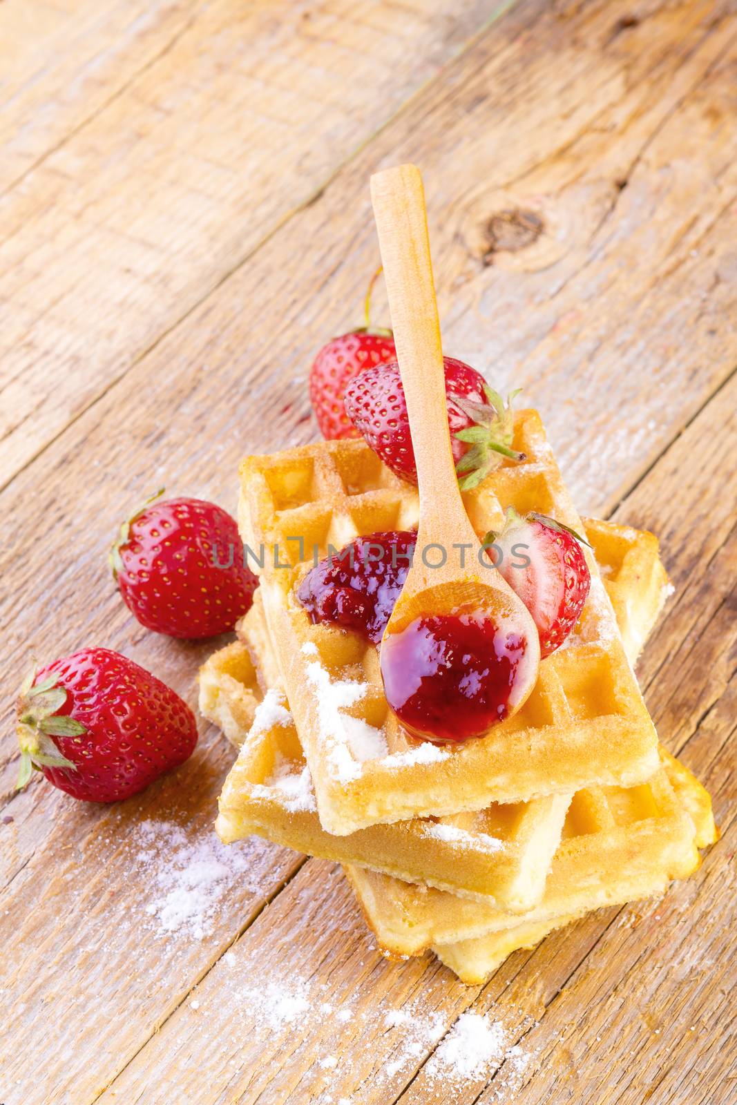 homemade waffles with strawberries maple syrup on wooden background