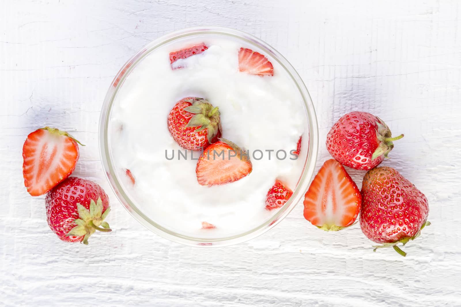 strawberry and yogurt in a wooden bowl on white wooden background