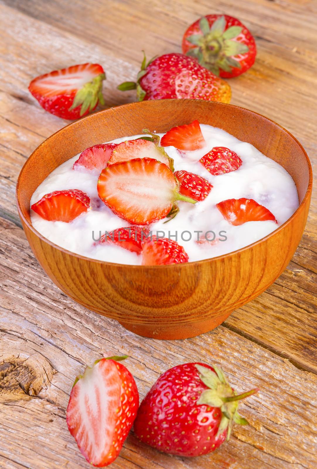 fresh organic greek yogurt with strawberries on wooden background