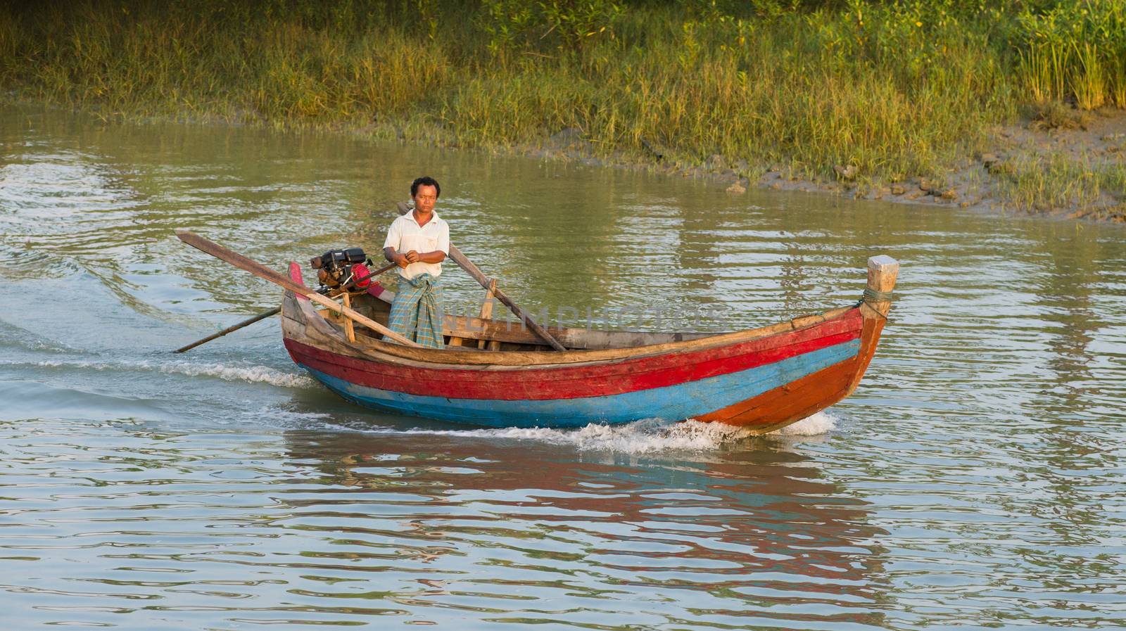 Sittwe, Rakhine State, Myanmar - October 16, 2014: Man navigating his motorboat on a canal near Sittwe, the capital of the Rakhine State in Myanmar.