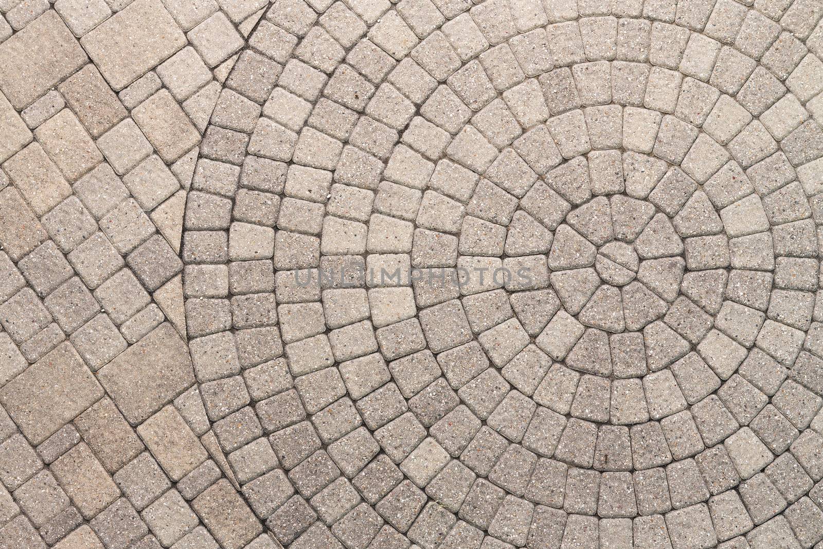 Paver bricks arranged in a circular pattern of concentric geometric circles. Architectural background of an ornamental pattern in outdoor patio paving.