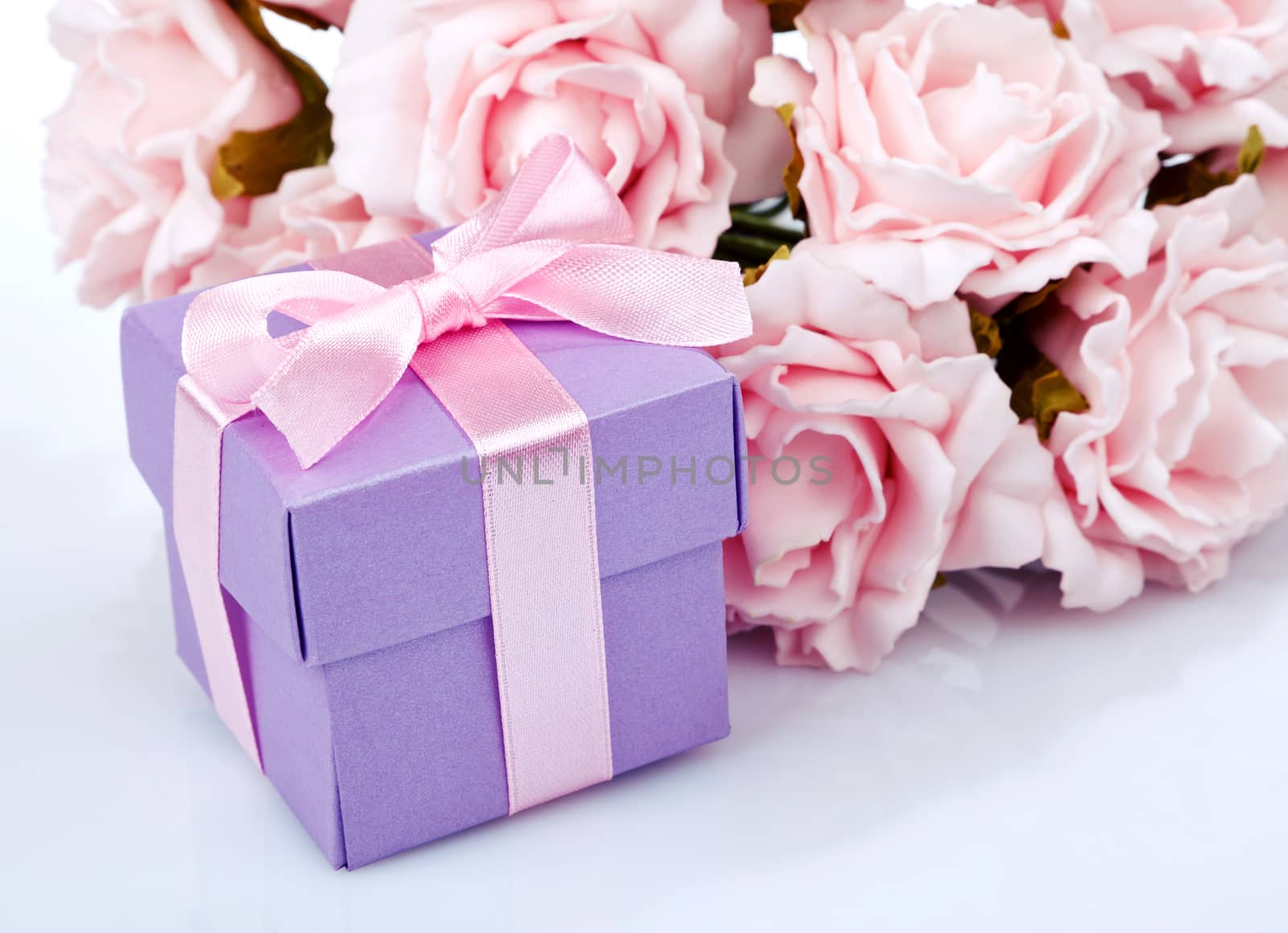 pink flowers and purple gift box with pink ribbon and bow on a white background