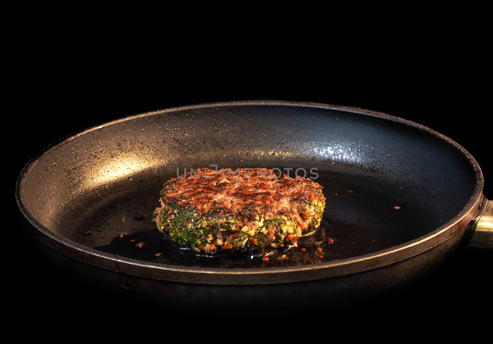 Frying seasoned hamburger in fry pan isolated on black by Arvebettum