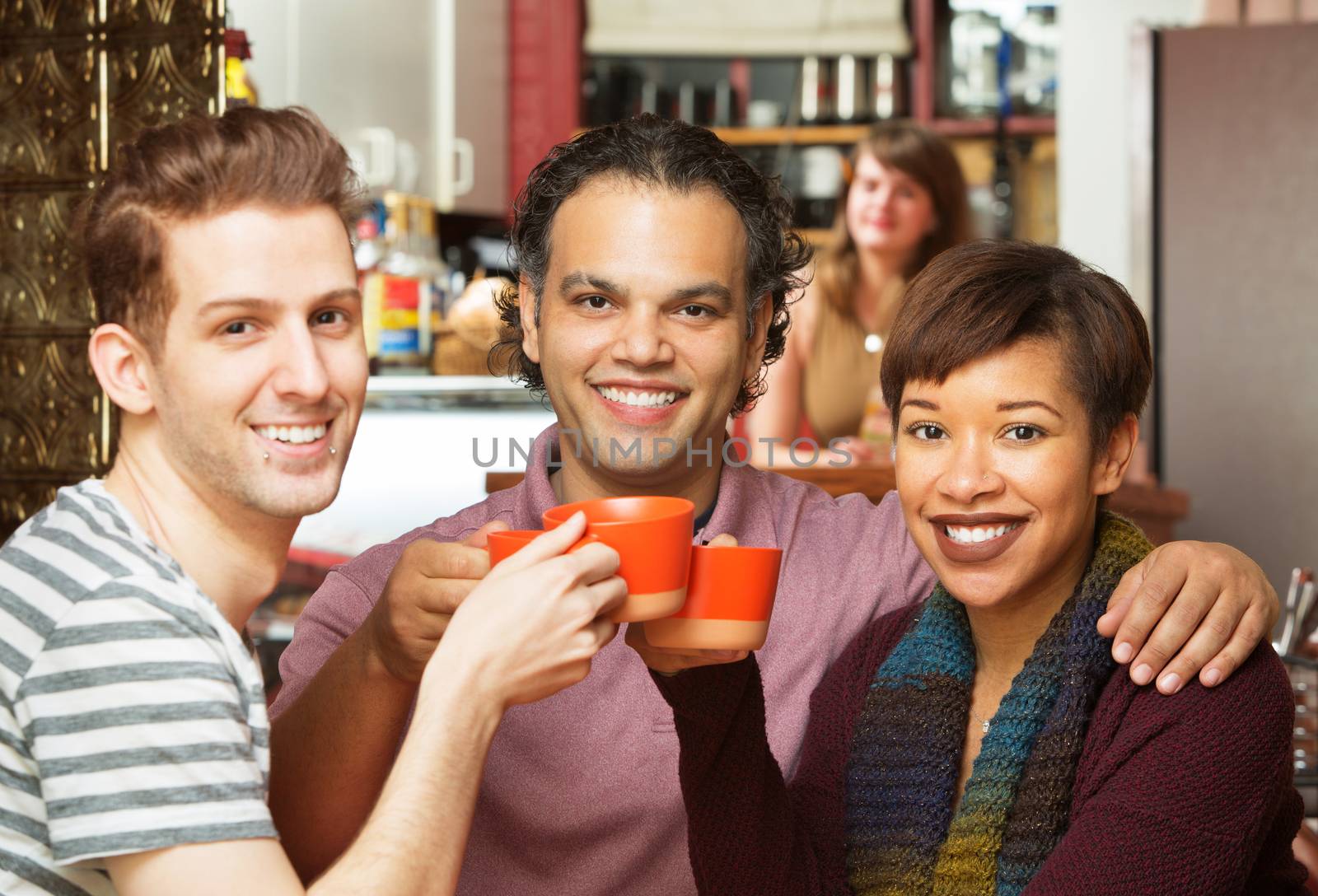 Group of three adults toasting coffee mugs in cafe