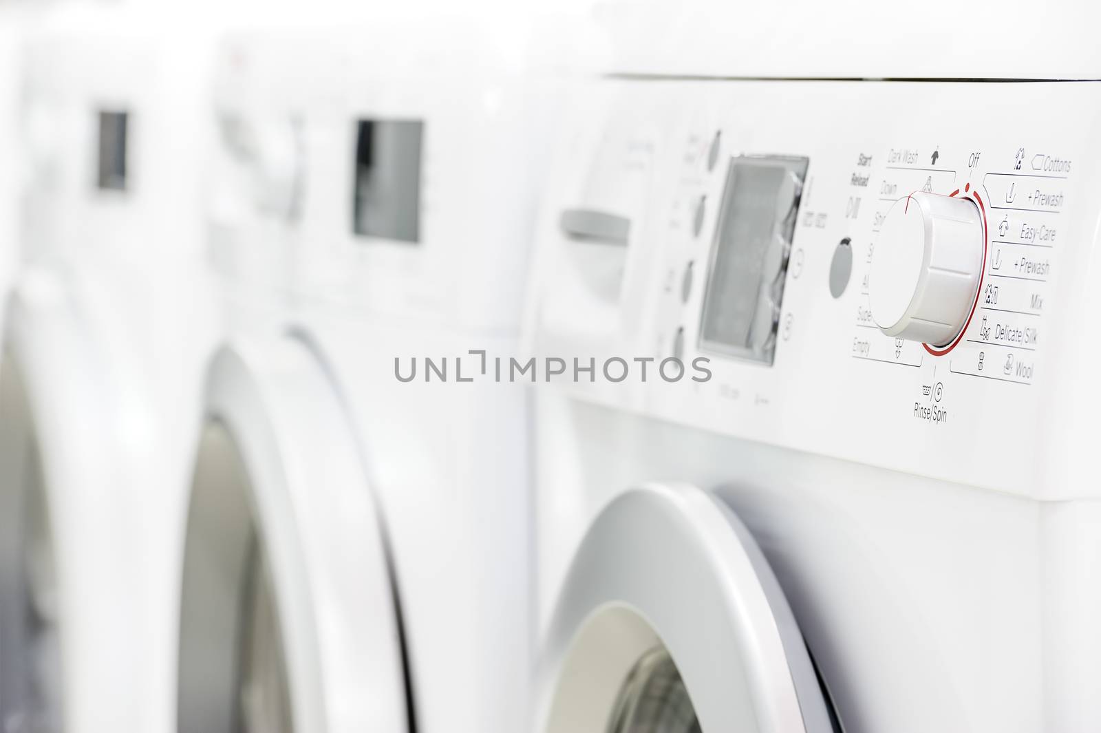row line of modern white laundry washing machines