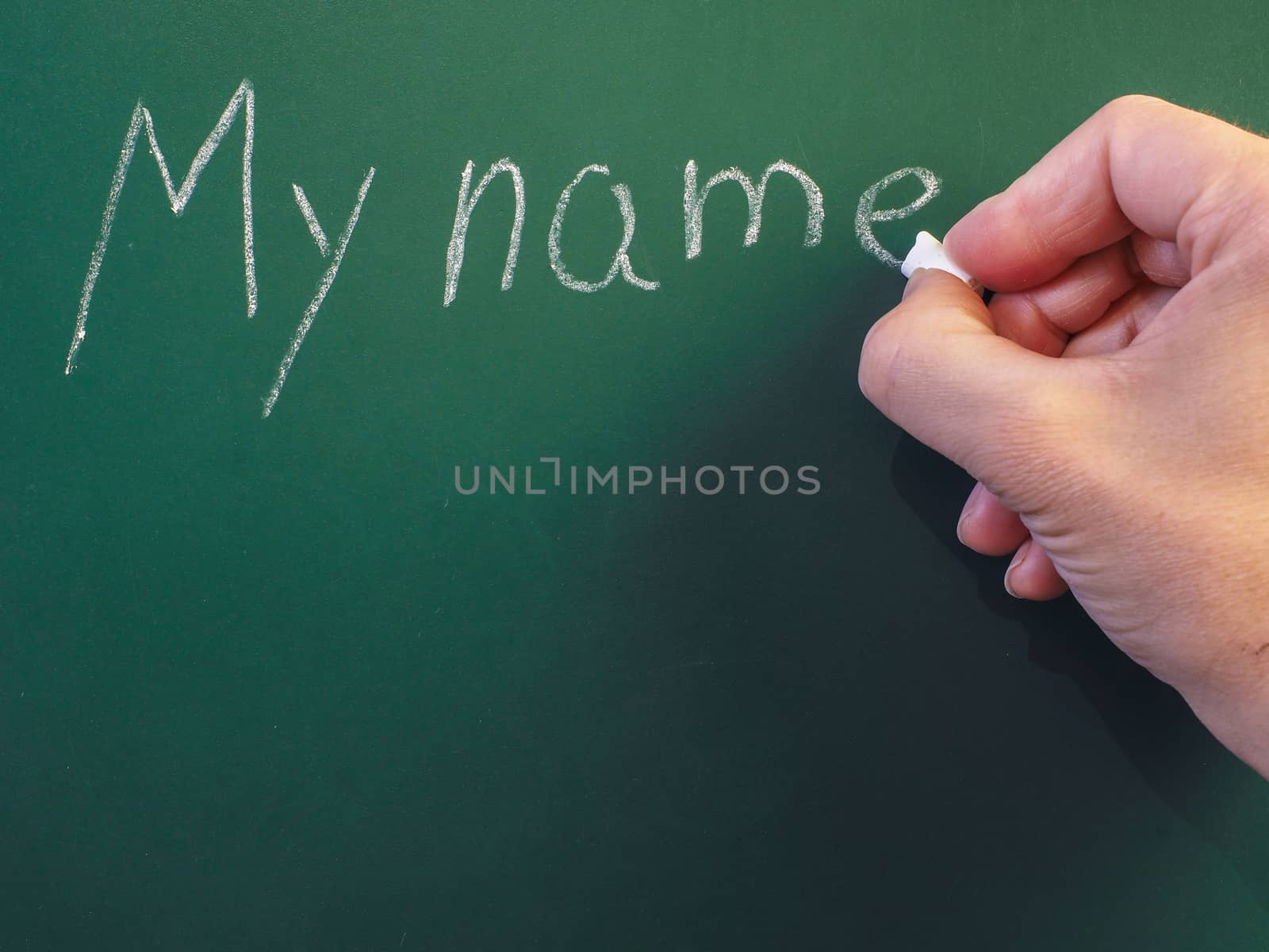 Person writing on green chalkboard; My name, with chalk