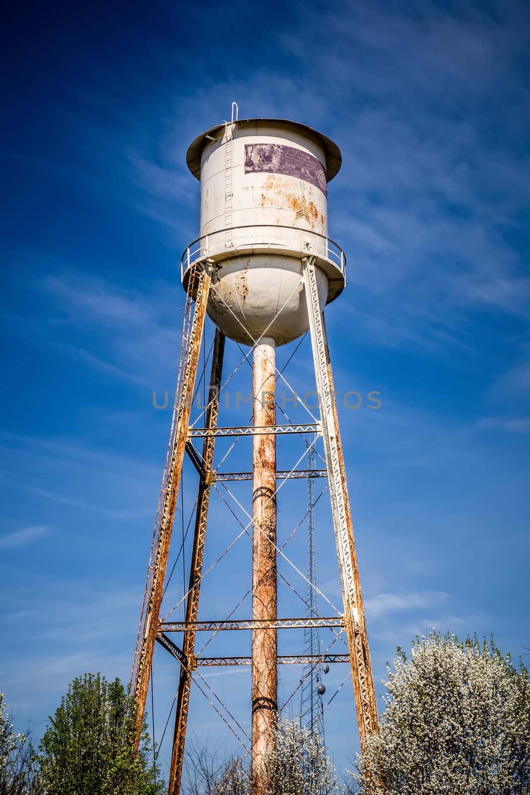 Tall  water tower with cloudy blue sky background by digidreamgrafix