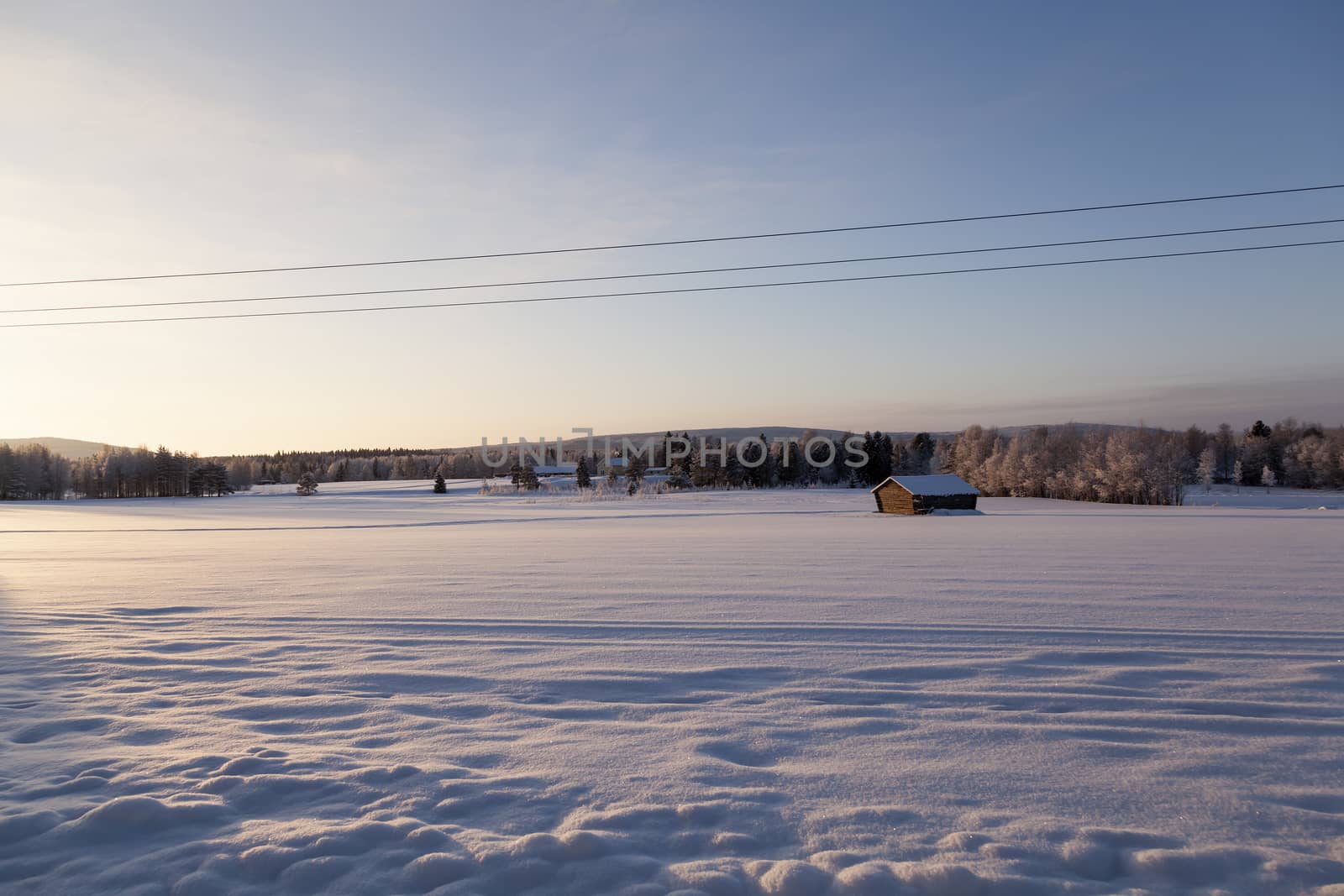 A barn and a big field of snow in the foreground