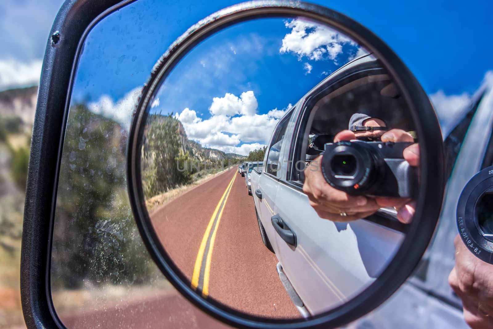  camera reflected in the rearview mirror of a car on a summer da by digidreamgrafix