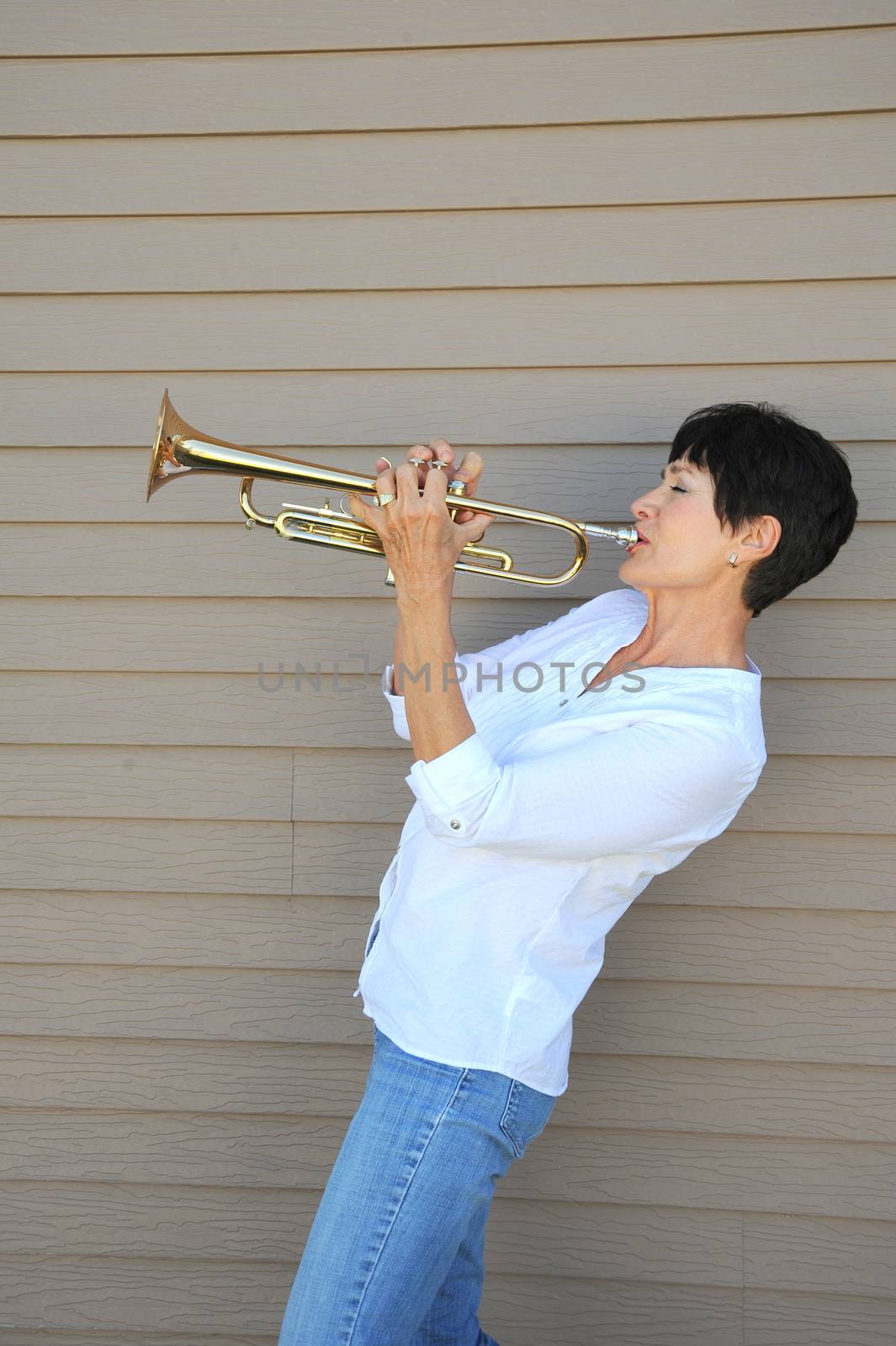 Mature female beauty blowing her trumpet outside.