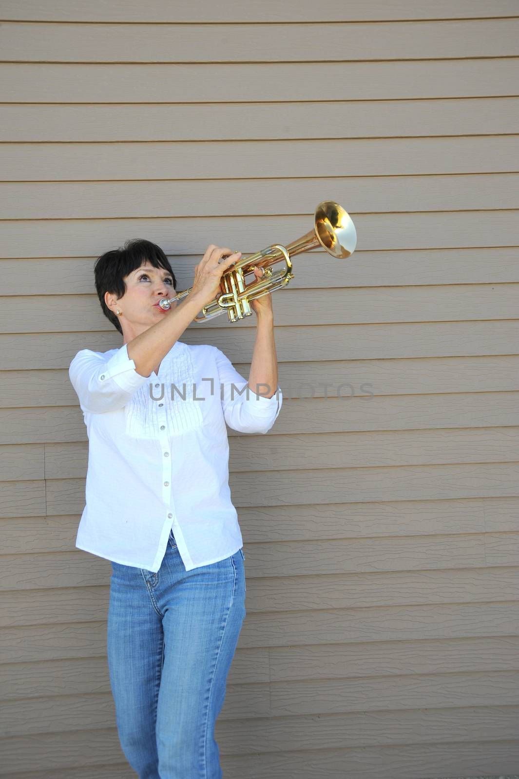 Mature female beauty blowing her trumpet outside.