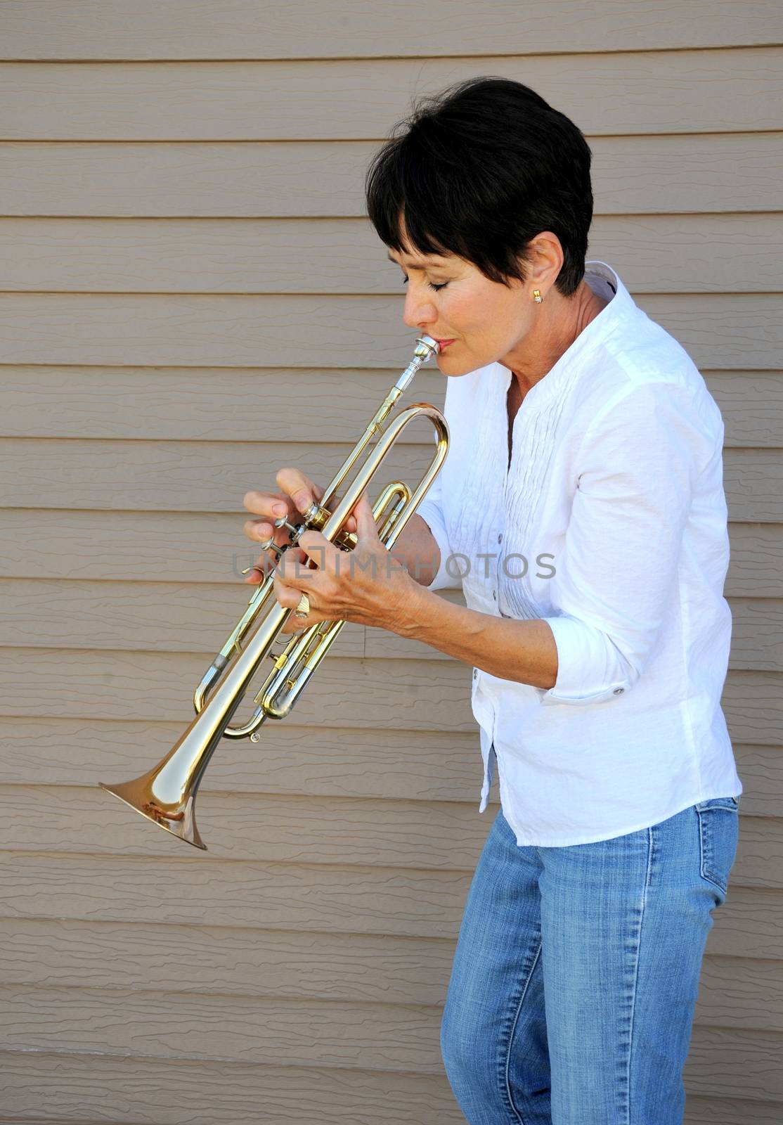 Mature female beauty blowing her trumpet outside.