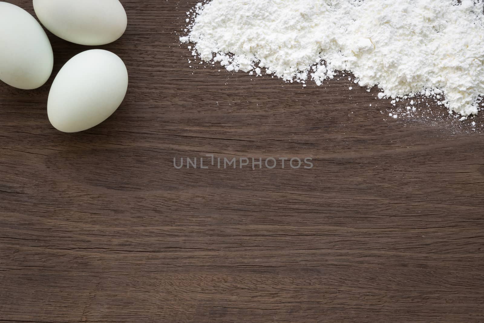 Top view of baking background with eggs and flour on vintage natural wood table. Rough texture and rustic surface with blank space for text.