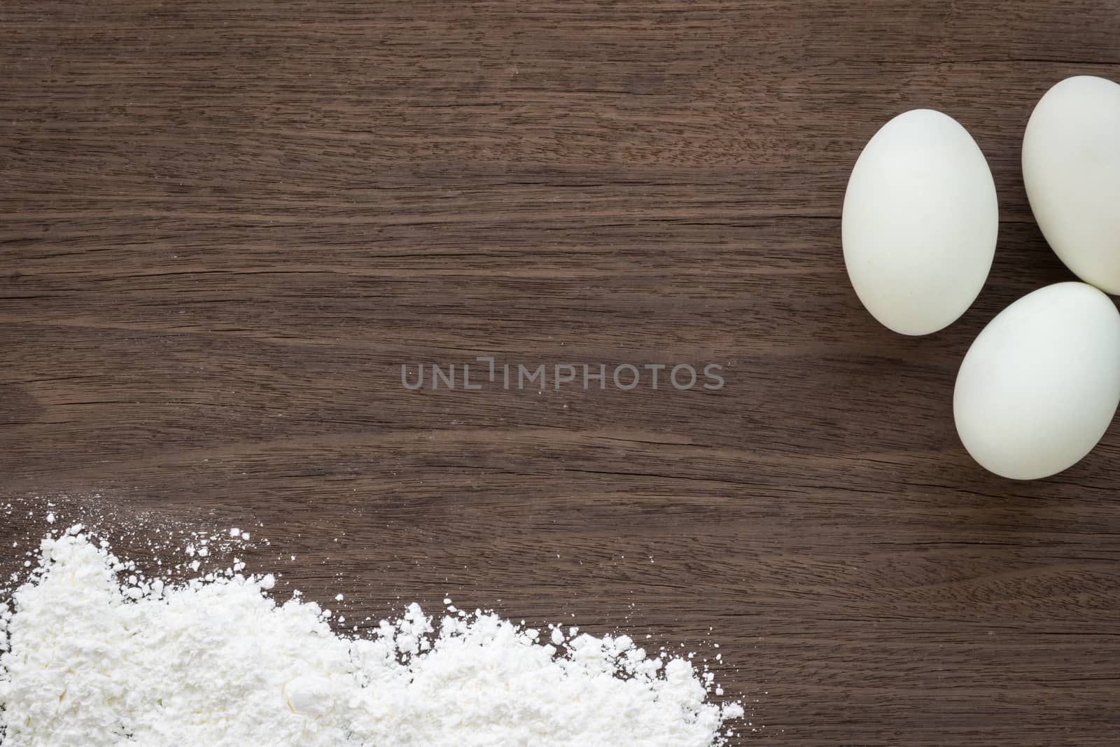 Top view of cooking background with eggs and  flour on vintage natural dark wood desk. Rough texture and rustic surface with free space for text.