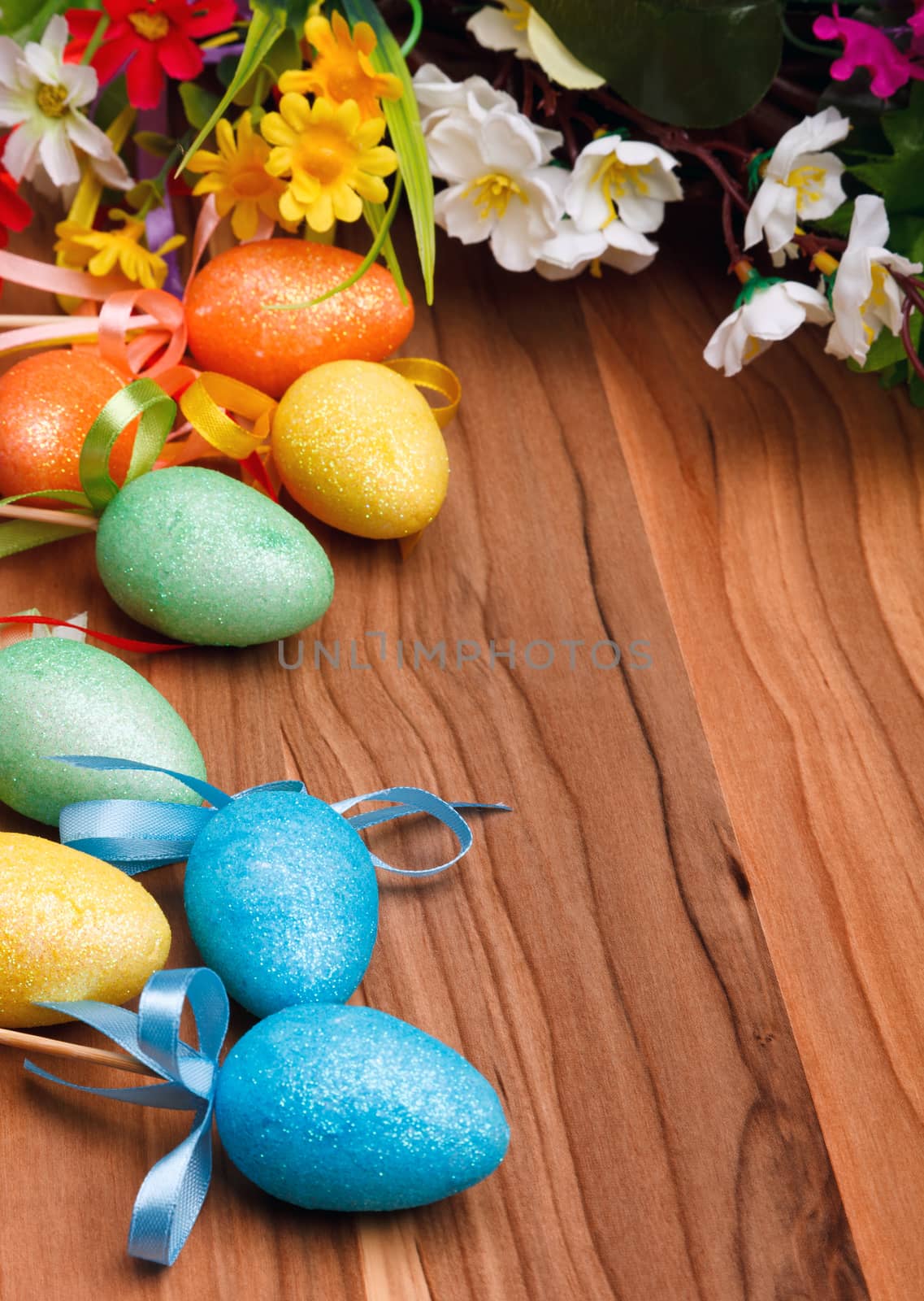 Easter flower arrangement and colorful eggs on wooden surface