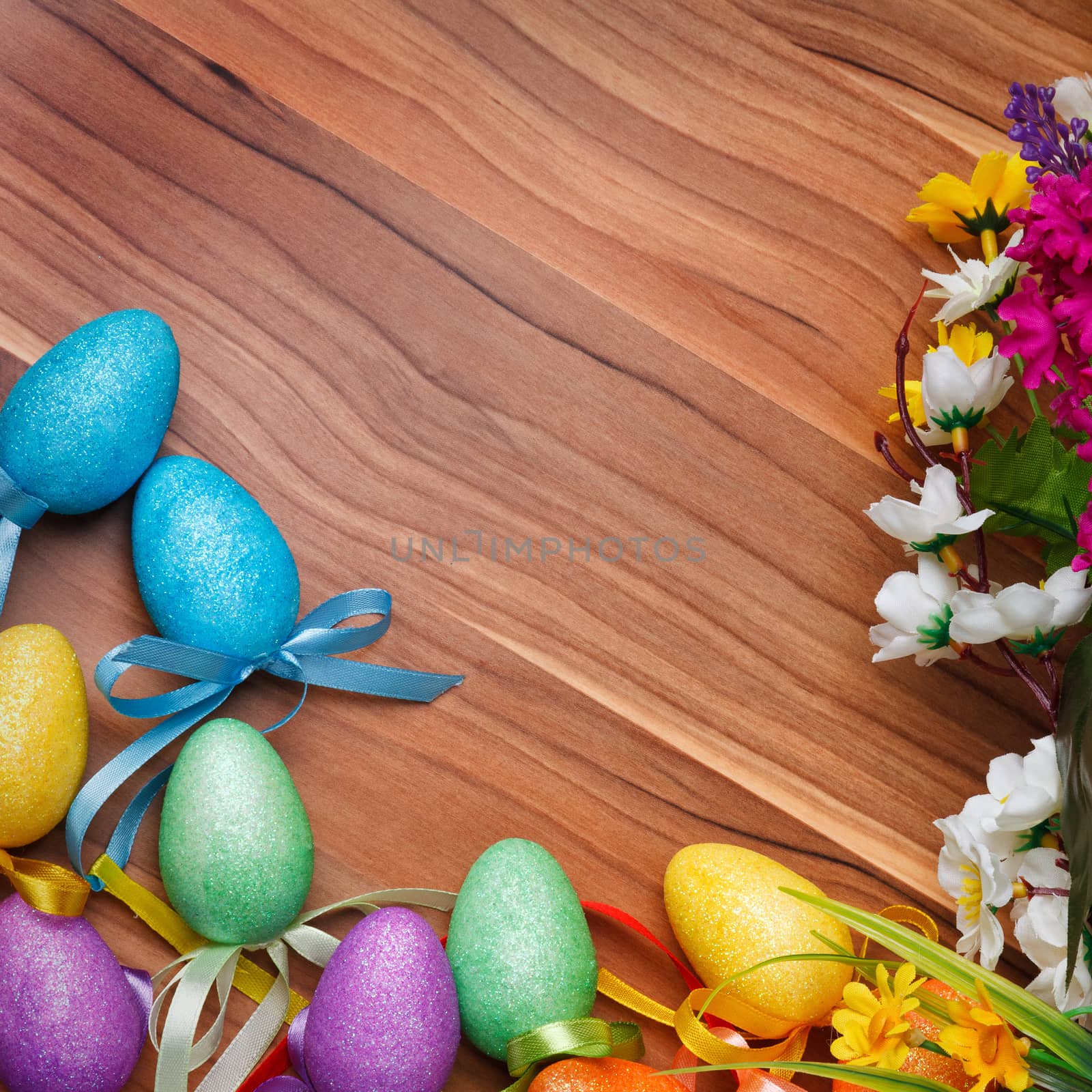 Easter flower arrangement and colorful eggs on a wooden surface with space for text