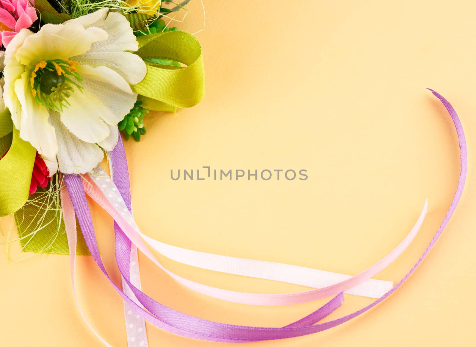 artificial flowers and streamers on cream background with place for label relamy