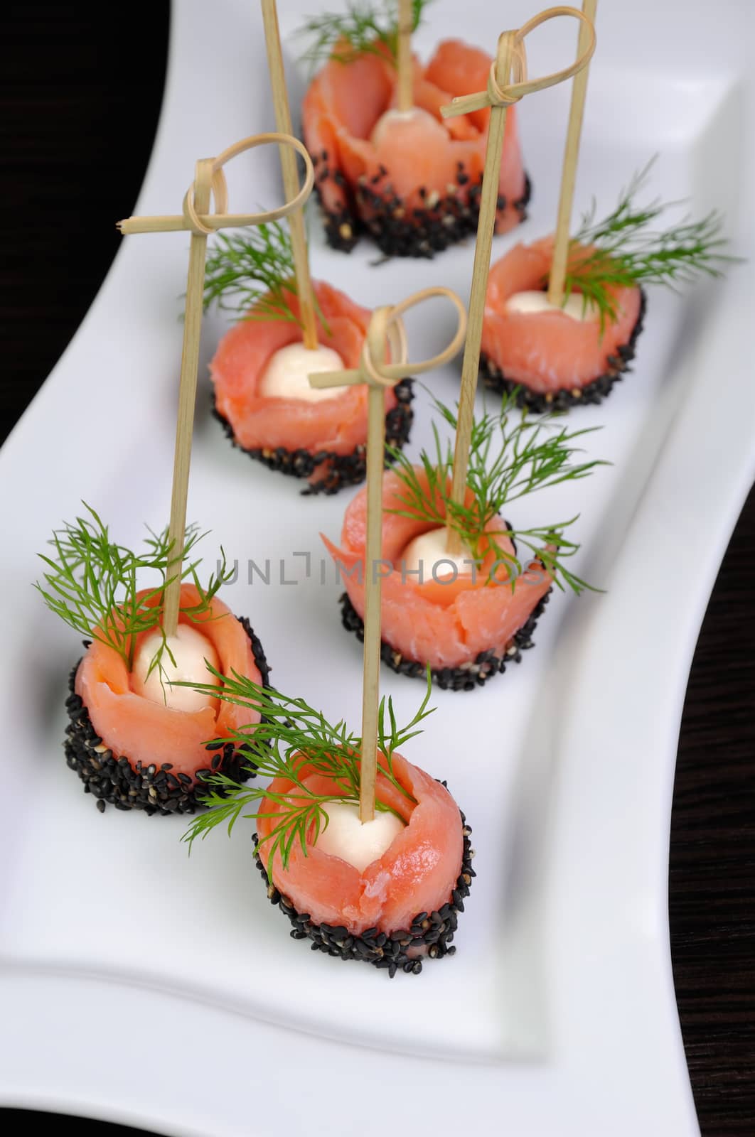 Appetizer of mozzarella wrapped slice of salted salmon with sesame
