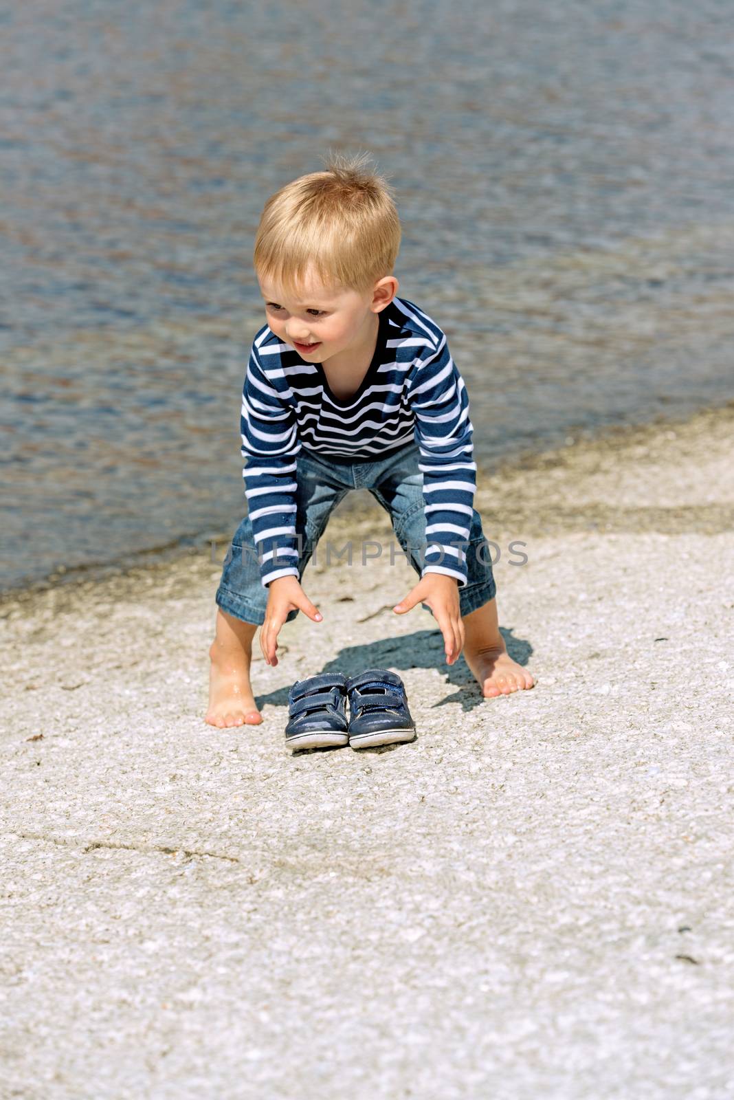 Little preschool boy playing on shore outdoors