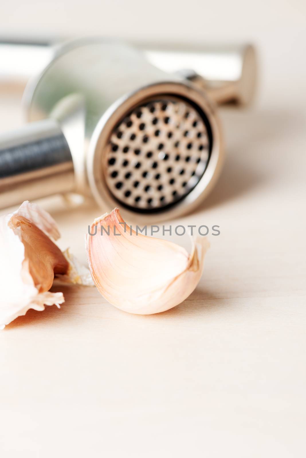 Garlic and garlic press on wooden table