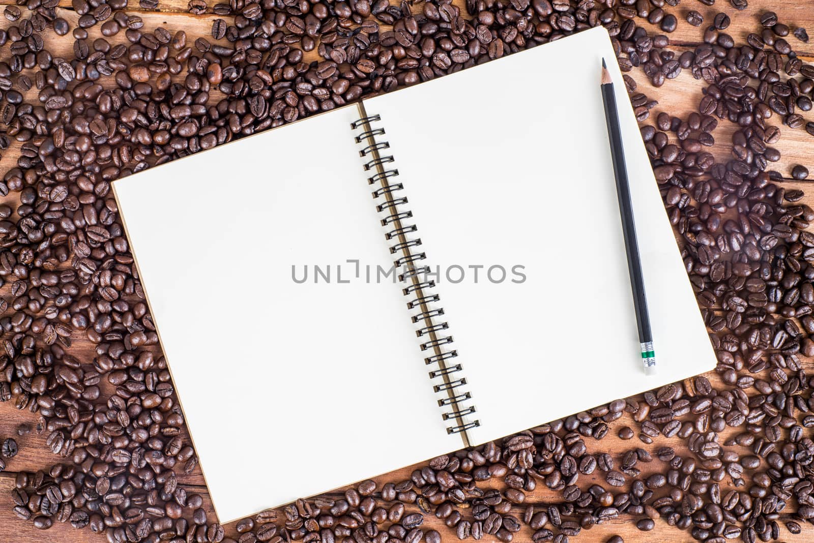 Pencil, notebook, coffee bean on wooden background by iamway