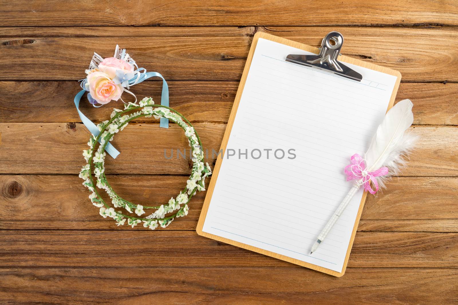 Wooden Clipboard attach planning paper with pen on top beside rose headband, tiara for bridesmaids