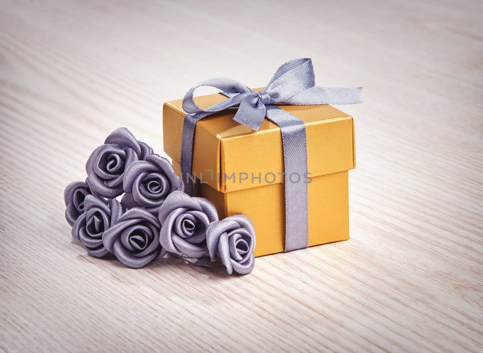 grey flowers and golden gift box with ribbon on wooden surface