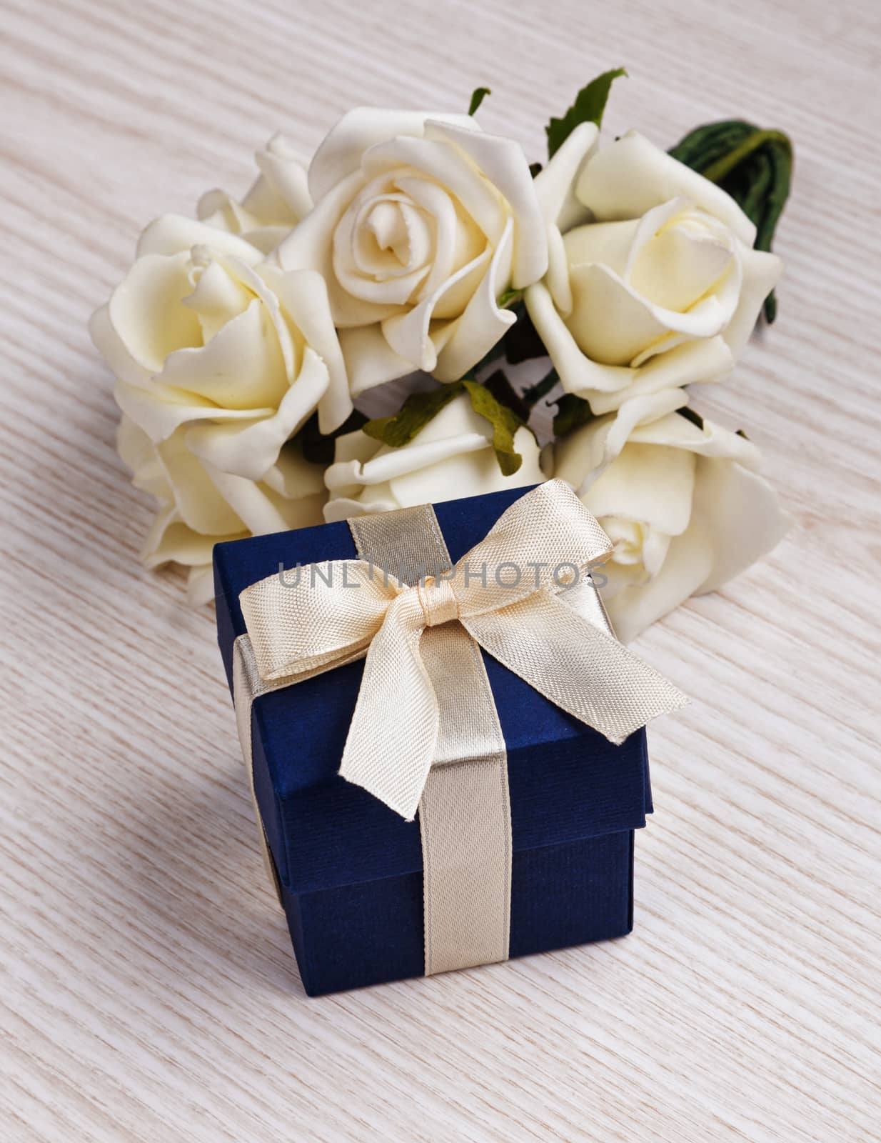 white flowers and blue gift box with white ribbon on wooden surface