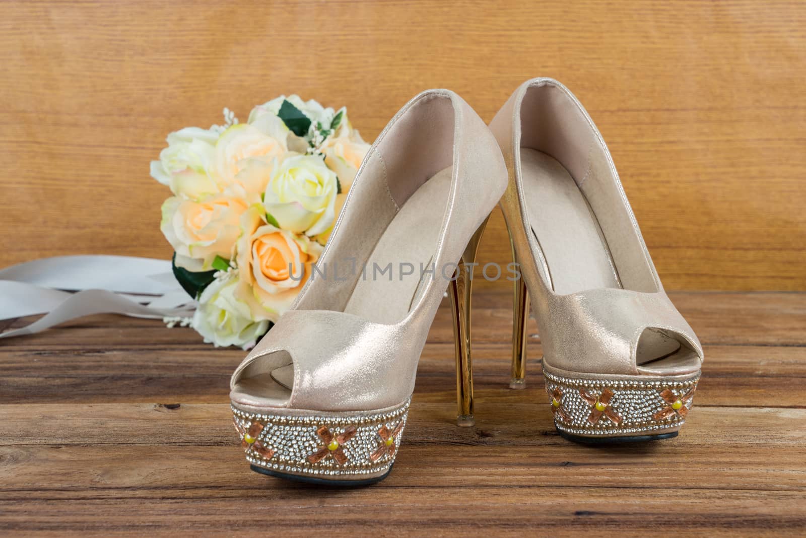 Wedding bouquet with bride's shoes on wood floor background