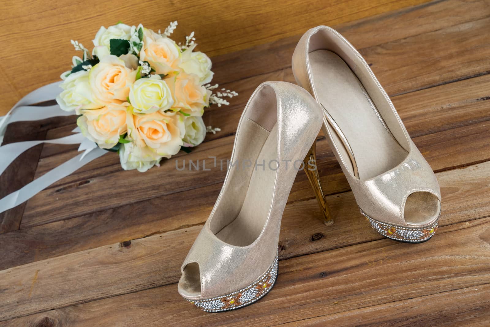 Wedding bouquet with bride's shoes on wood floor background