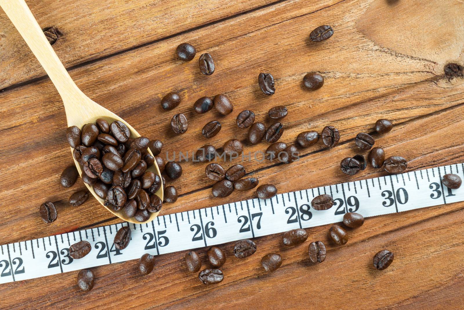 Coffee bean on wooden spoon and tape measure on wooden table background