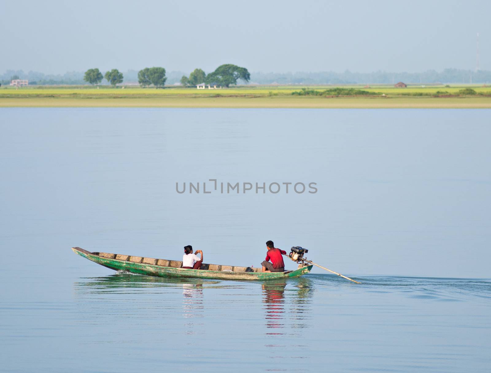 Sittwe, Rakhine State, Myanmar - October 16, 2014: Couple in a traditional, wooden longtail boat travelling down the Kaladan River at the Rakhine State in Myanmar.