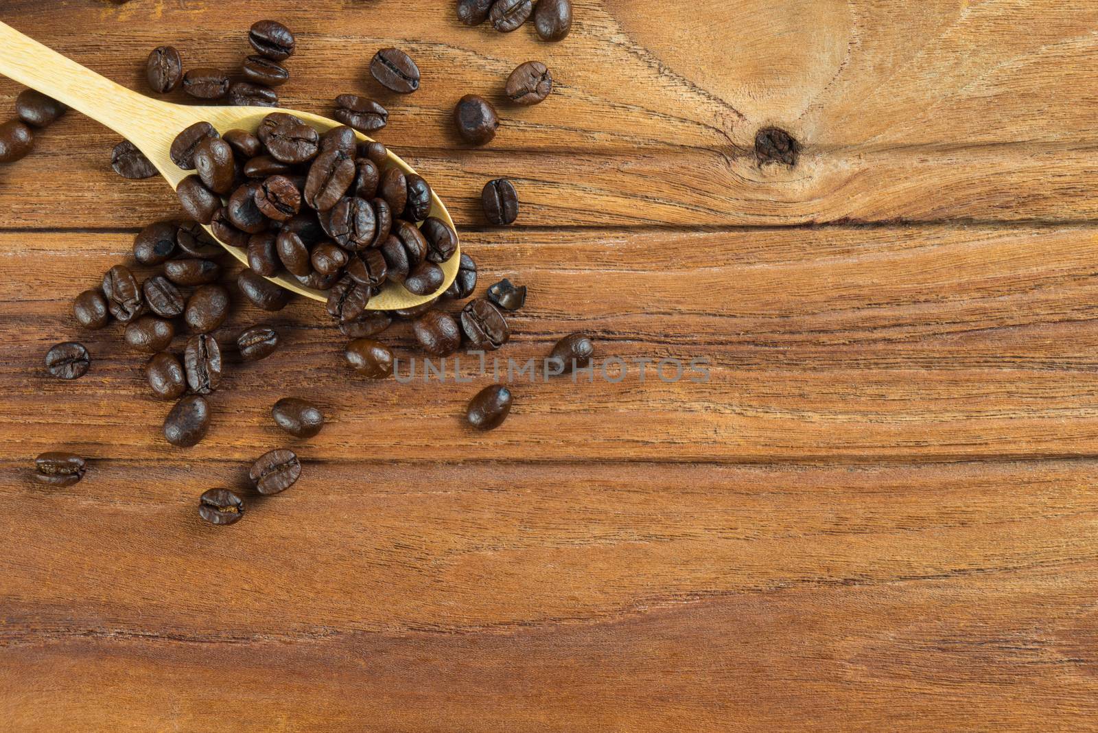 Coffee bean on wooden spoon and wooden table background