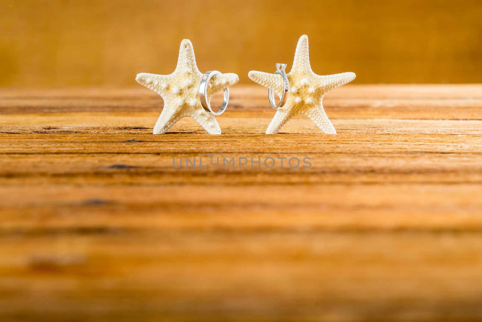 Two wedding rings with two starfish on wooden table by iamway