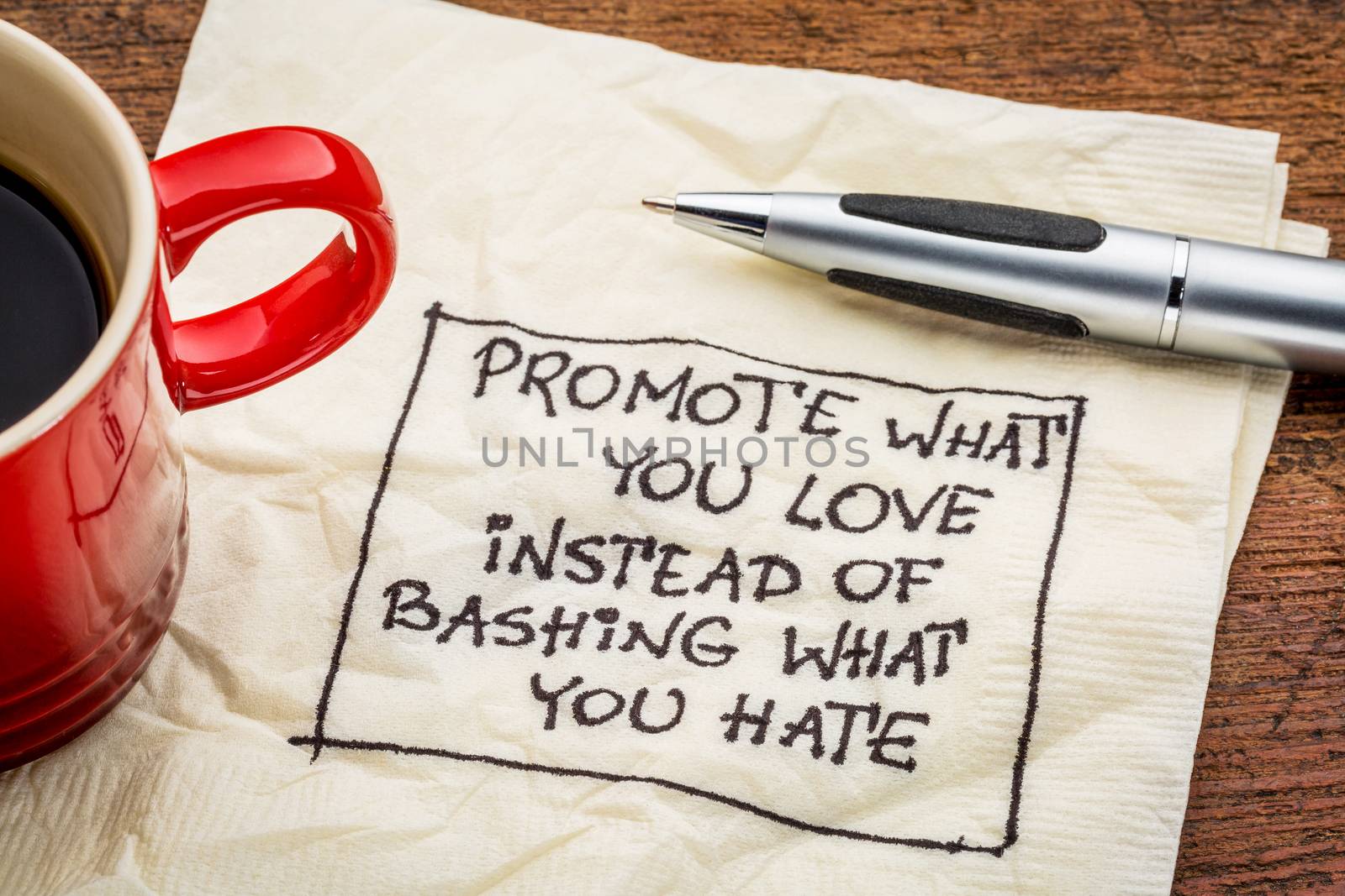 Promote what you love instead of bashing what you hate - handwriting on a napkin with cup of coffee