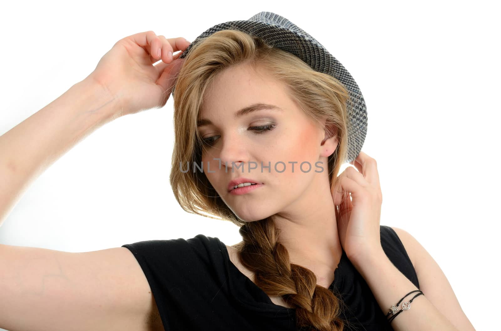 Young, pretty female model. Blonde girl putting hat and holding it with her hands.