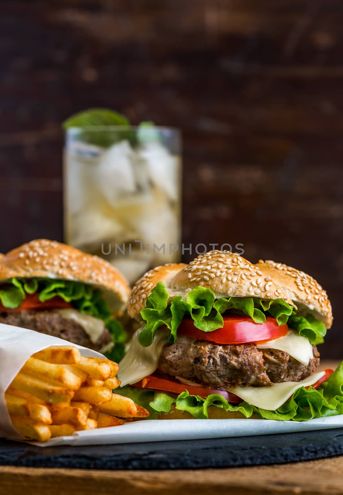 Closeup of Homemade Hamburger with Fresh Vegetables and Drink with Ice in Background