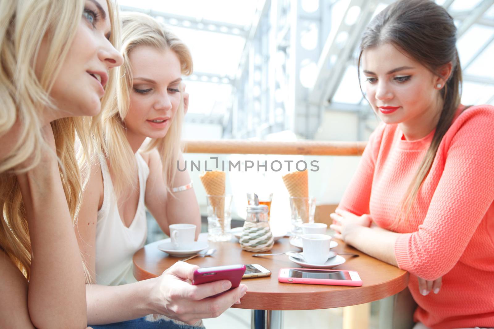 Group of young women sitting in cafe with gadgets