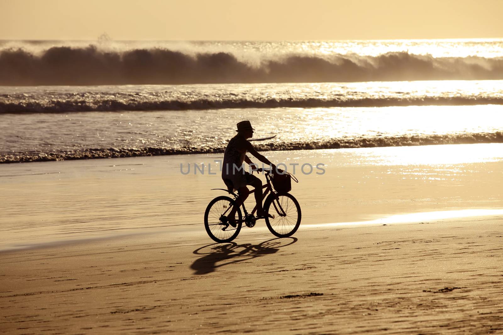 Woman on a bicycles goes on seacoast. Bali, Indonesia