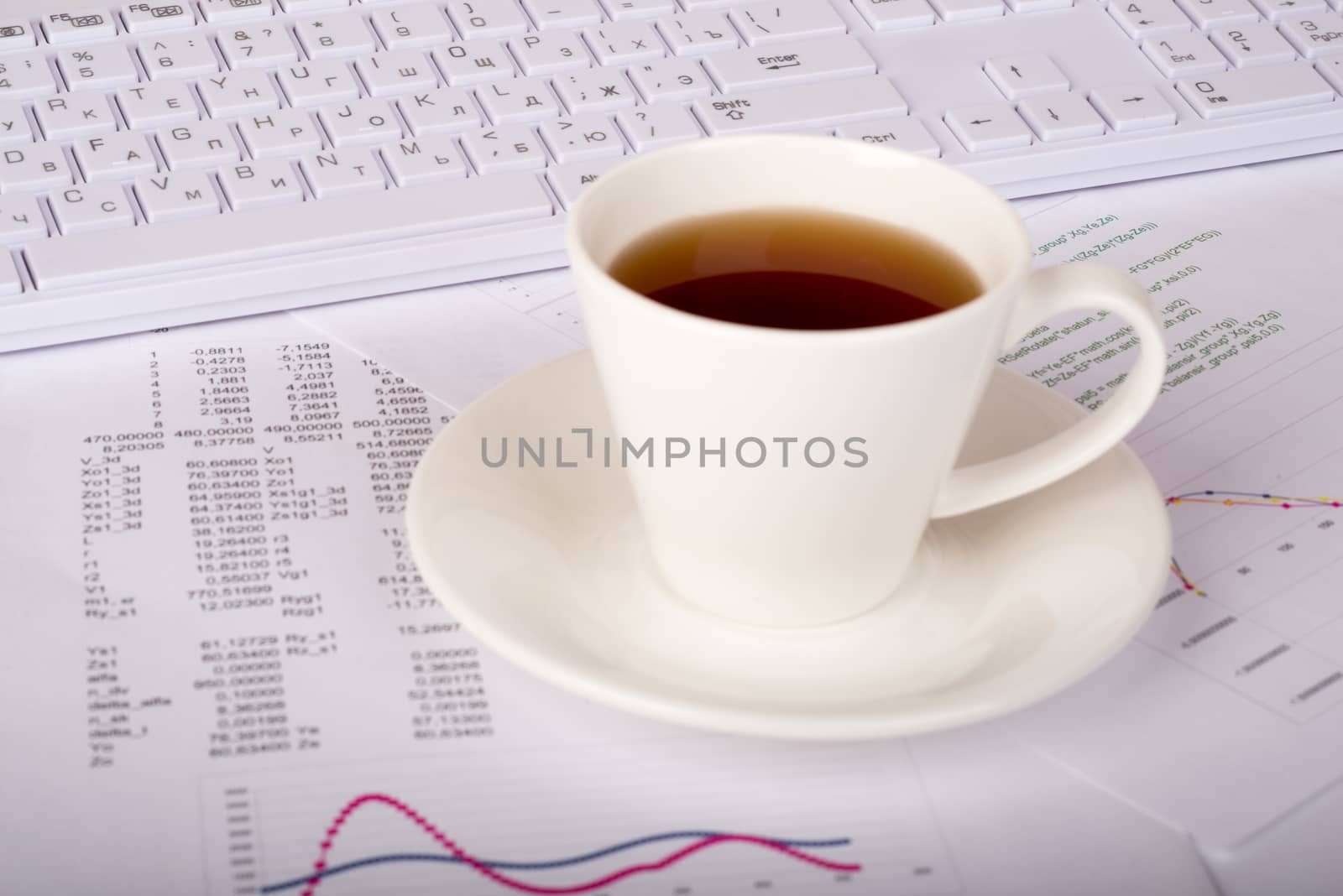 White keyboard with coffee cup and documents, side view