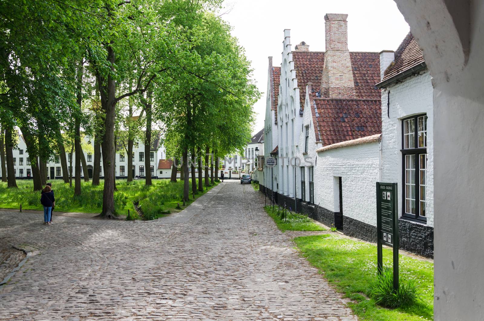 Bruges, Belgium - May 11, 2015: People visit White houses in the Beguinage in Bruges by siraanamwong